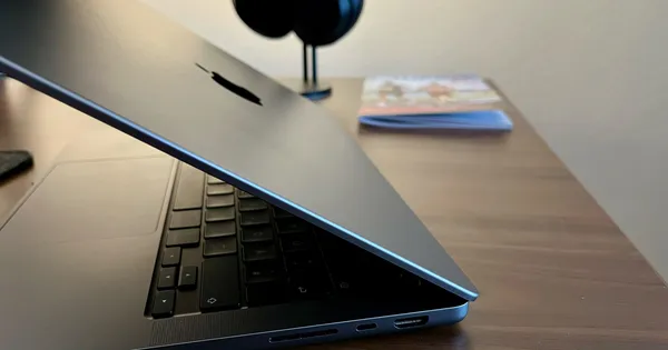 MacBook Pro auf einem Schreibtisch, mit Kopfhörern und einem 2025er Laufkalender im Hintergrund.